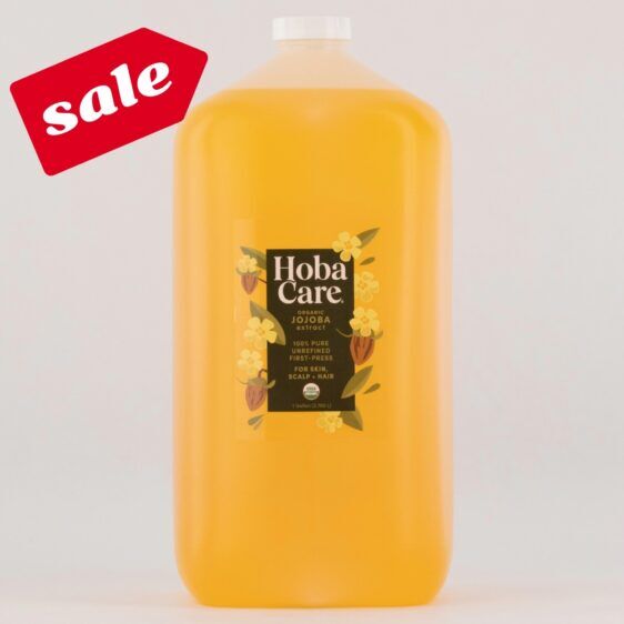 OG 128 oz SALE 128 fl oz bottle of golden HobaCare organic Jojoba on light gray background