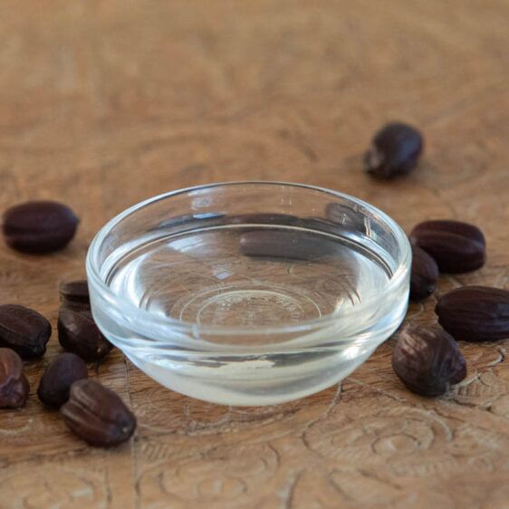 Clear deodorized jojoba in small bowl with jojoba seeds around square