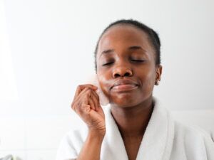 black woman doing facial gua sha massage with pink stone