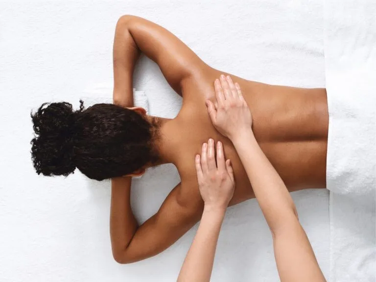 hands massage dark skinned woman's bask to promote jojoba oil as a massage medium