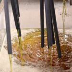 golden unrefined jojoba coming out of nozzles after being pressed through an expeller press at processing facility