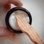 video of jojoba butter being removed from glass jar with a wooden spatula to show buttery texture