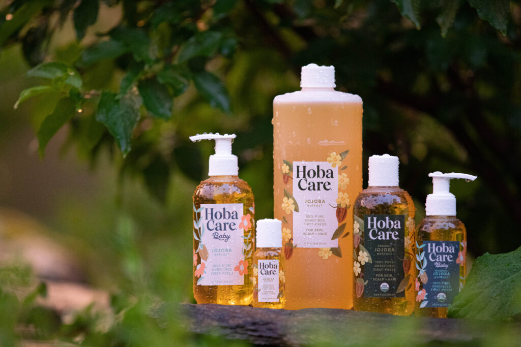 bottles of golden hobacare jojoba oil in various sizes at the golden hour after rain
