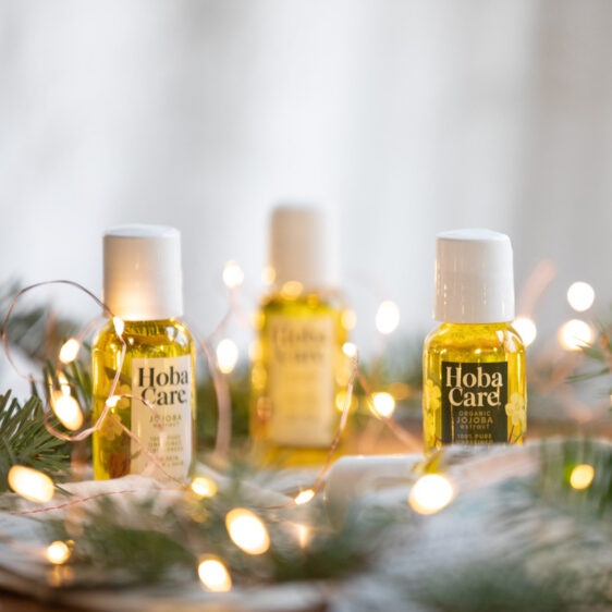 one ounce bottles of HobaCare Jojoba surrounded by balsam and warm fairy lights