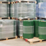green 55 gallon drums of golden jojoba stacked in warehouse