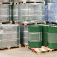 green 55 gallon drums of golden jojoba stacked in warehouse
