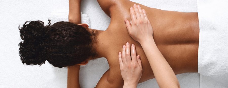 hands massage dark skinned woman's bask to promote jojoba oil as a massage medium